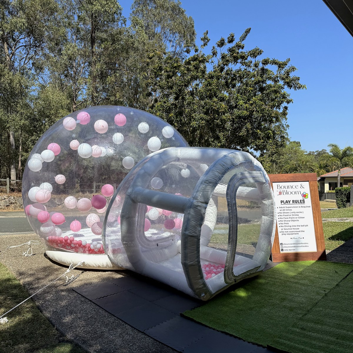 Clear bubble dome with balloons floating inside, set up on a lawn