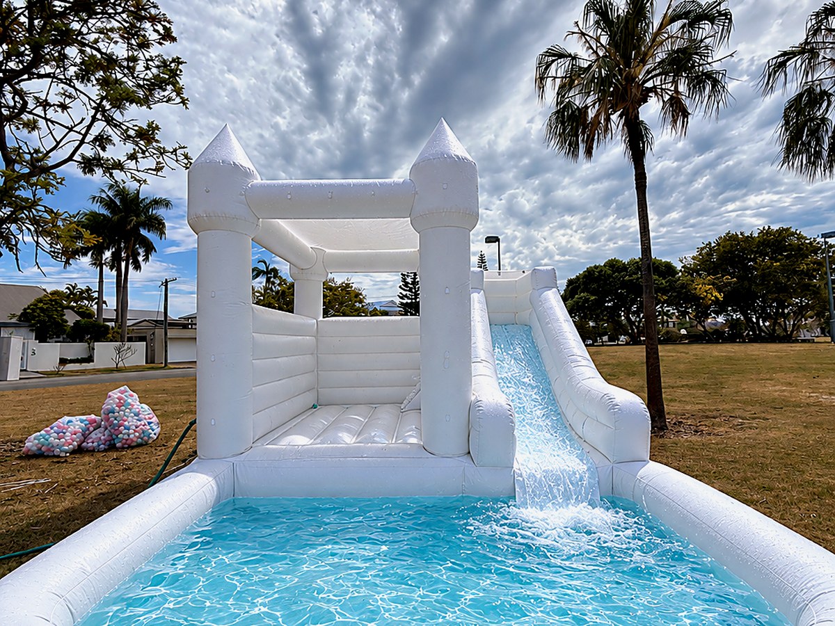 Water slide on a white jumping castle running into a full splash pool