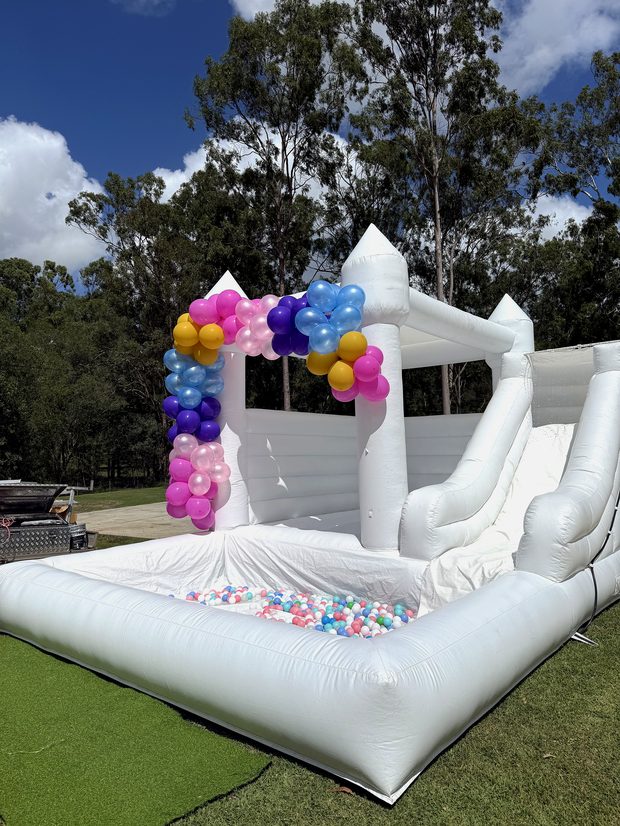 White castle with a colourful balloon garland and ball pit