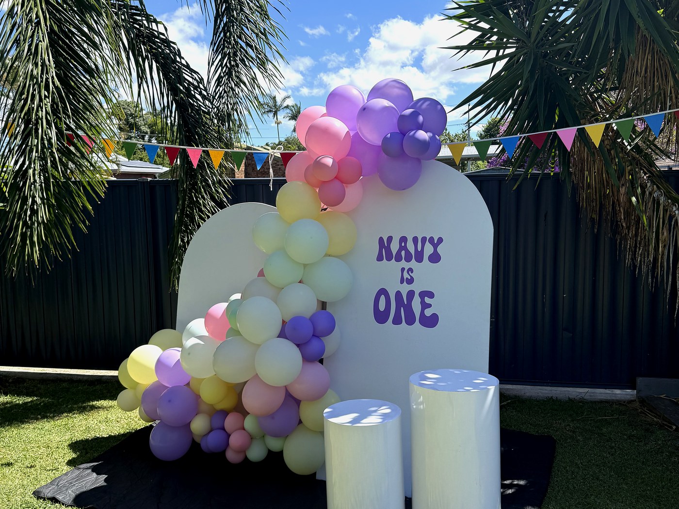 Pastel balloon garland on an arch backdrop with plinths